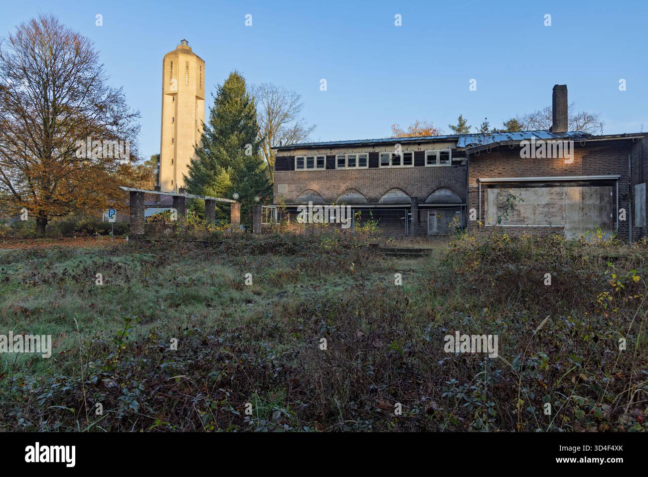 L'area industriale abbandonata di radio Kootwijk con l'alta torre dell'acqua e un edificio in mattoni sopraelevato e fatiscente in primo piano. Foto Stock