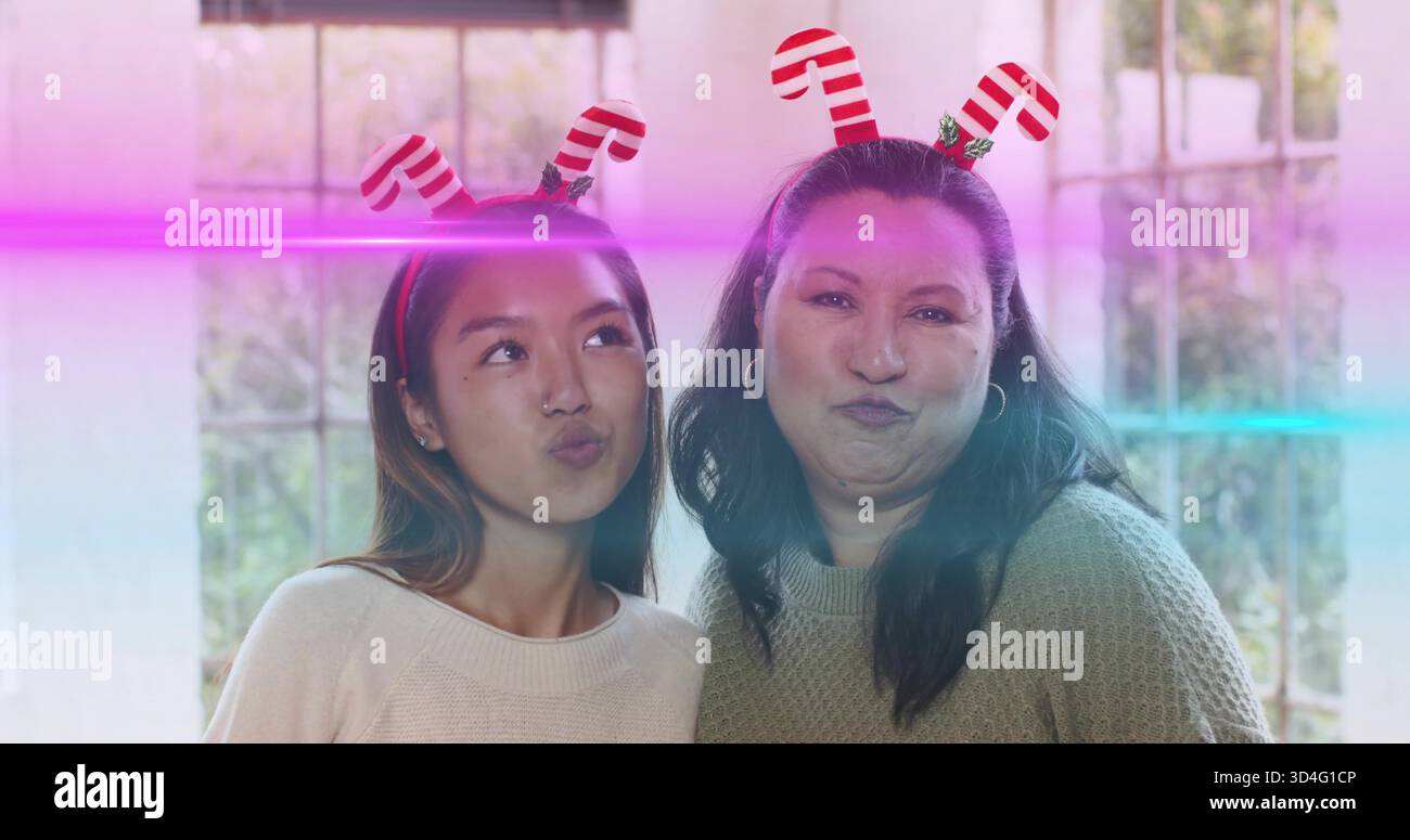 Puckering due donne che si appoggiano vicino alla finestra a più vetri, indossano fasce in canna di caramelle e maglioni in maglia Foto Stock