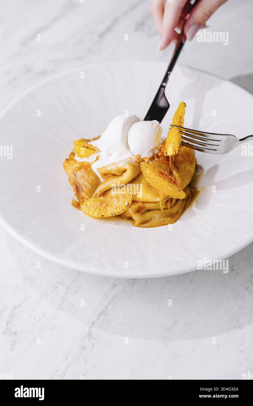 Cibo, deliziosi pancake, cucchiaio di gelato con scorza d'arancia, forchetta in azione Foto Stock