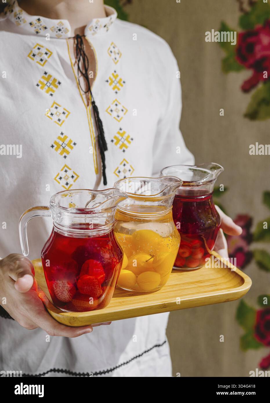 Cibo, la persona presenta tre caraffe di acqua fresca infuso di frutta su un vassoio di legno Foto Stock