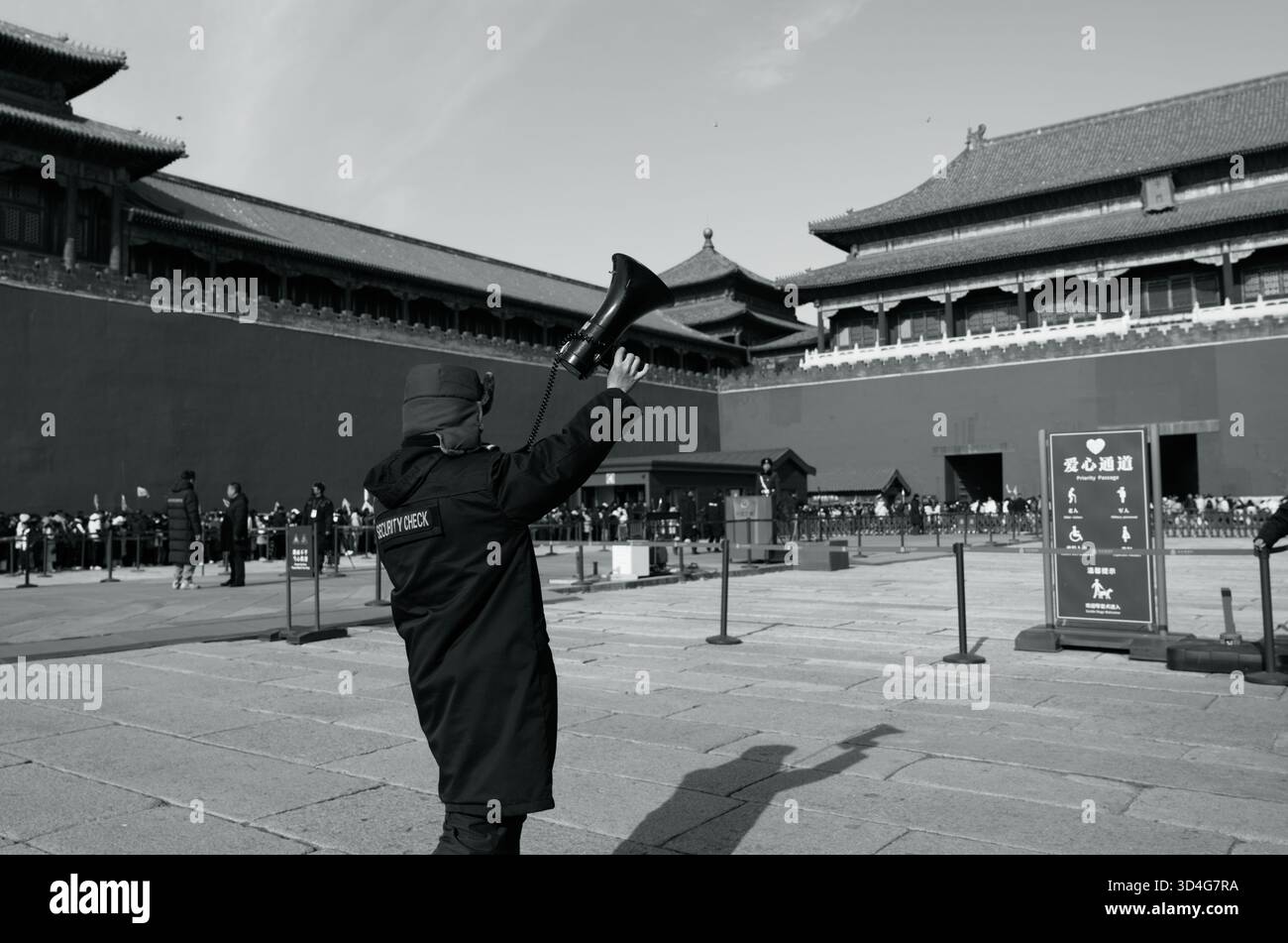 Scena di sicurezza in bianco e nero nella città Proibita, personale con megafono che dirige le linee di ingresso Foto Stock