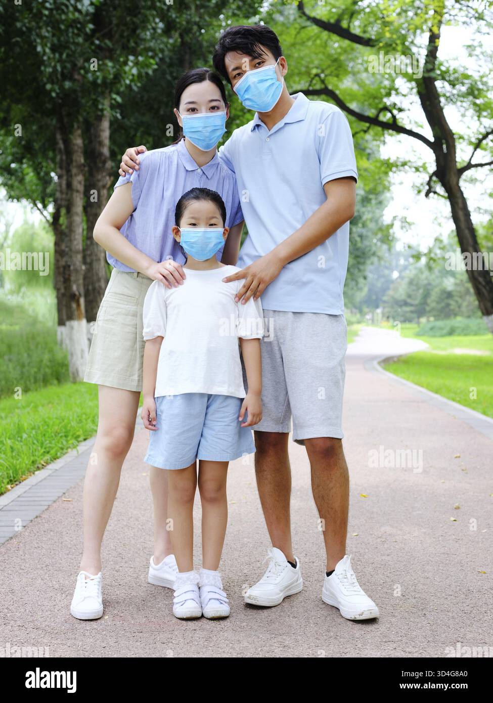 Una famiglia di tre persone con maschere all'aperto Foto Stock