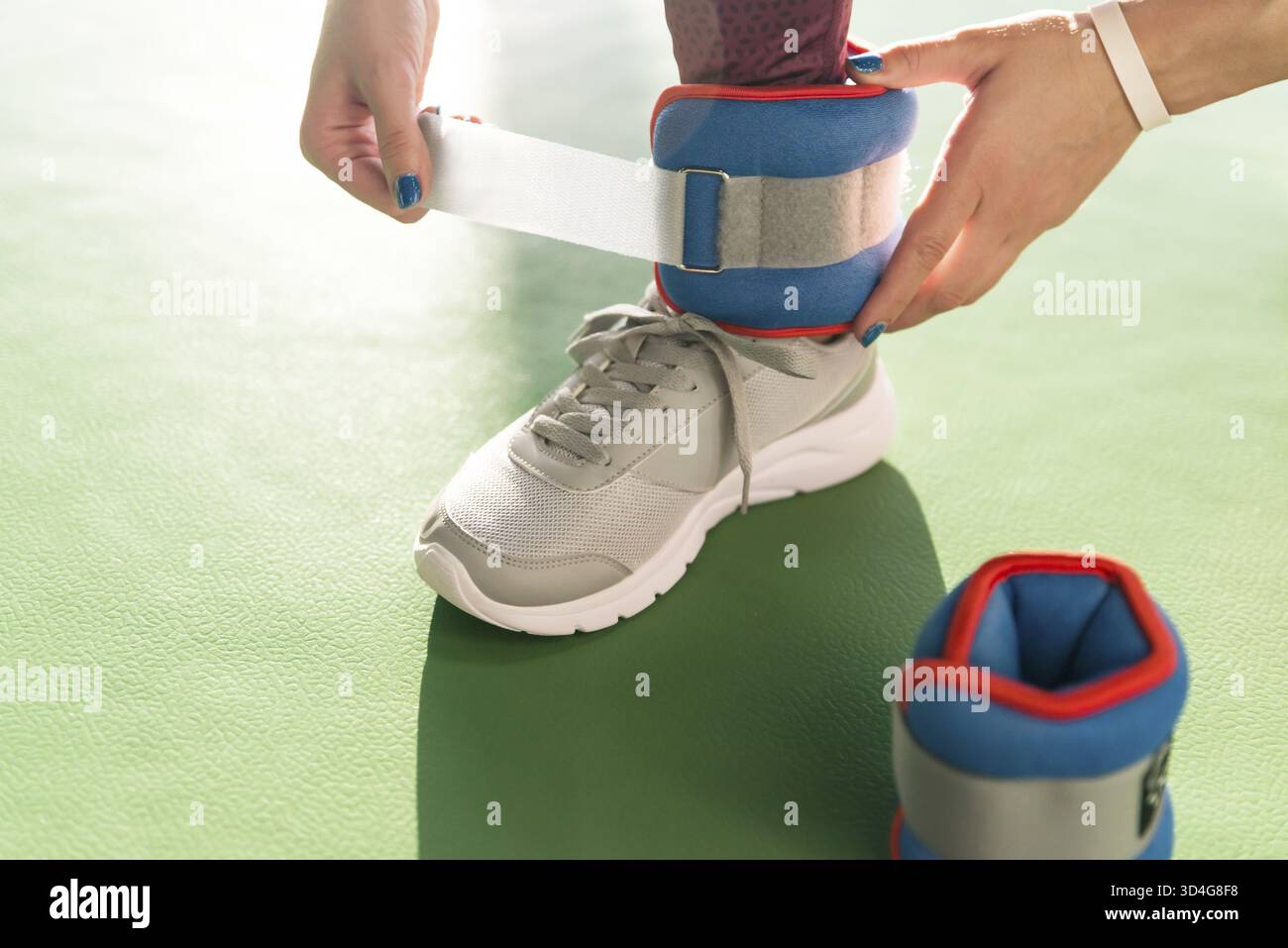 Donna mettendo sulla caviglia wights prima che lei inizia un allenamento in palestra fitness e salute Foto Stock