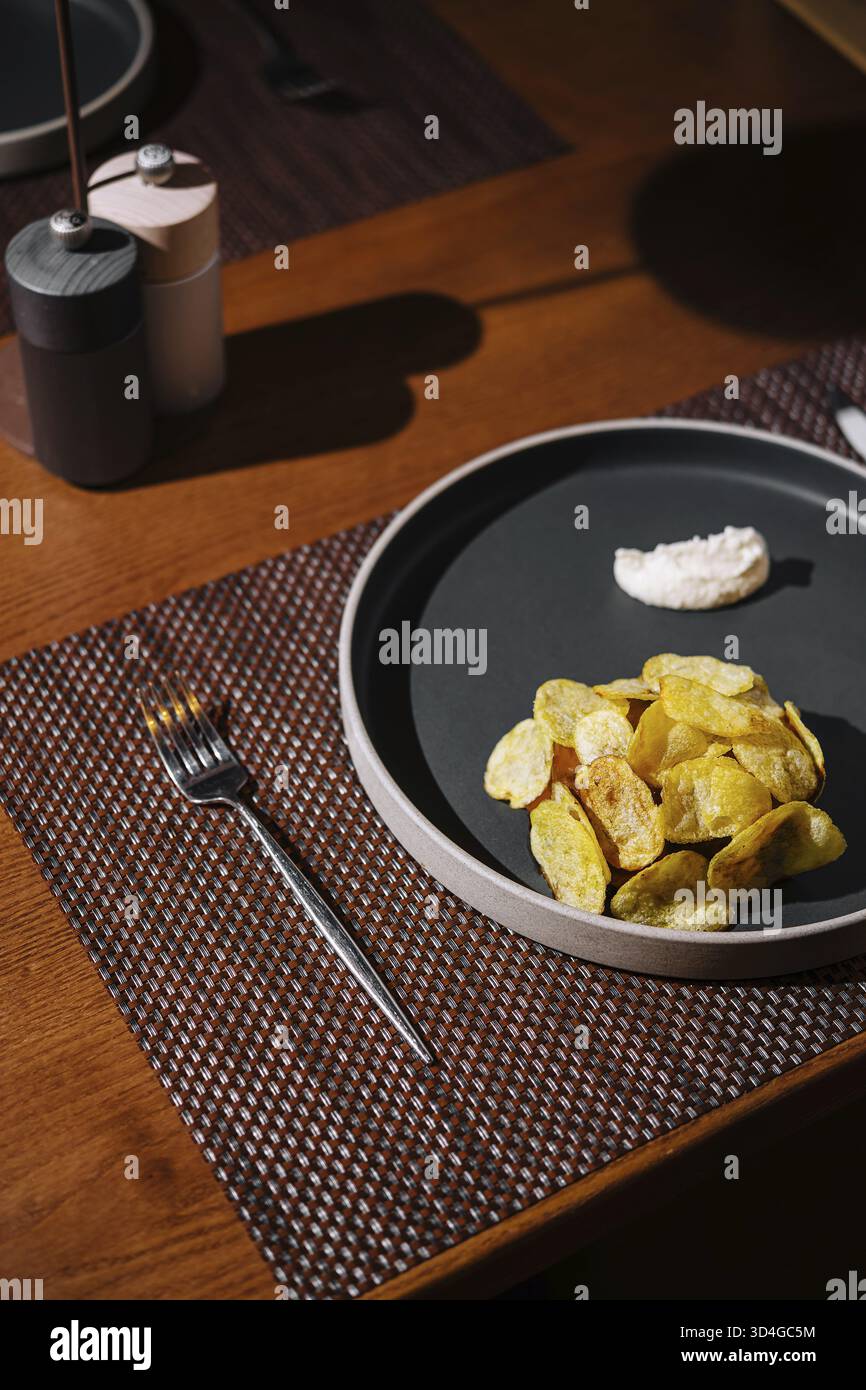 Cibo, moderno tavolo da pranzo con un piatto di patatine artigianali e un lato di immersione in un elegante ambiente ristorante Foto Stock