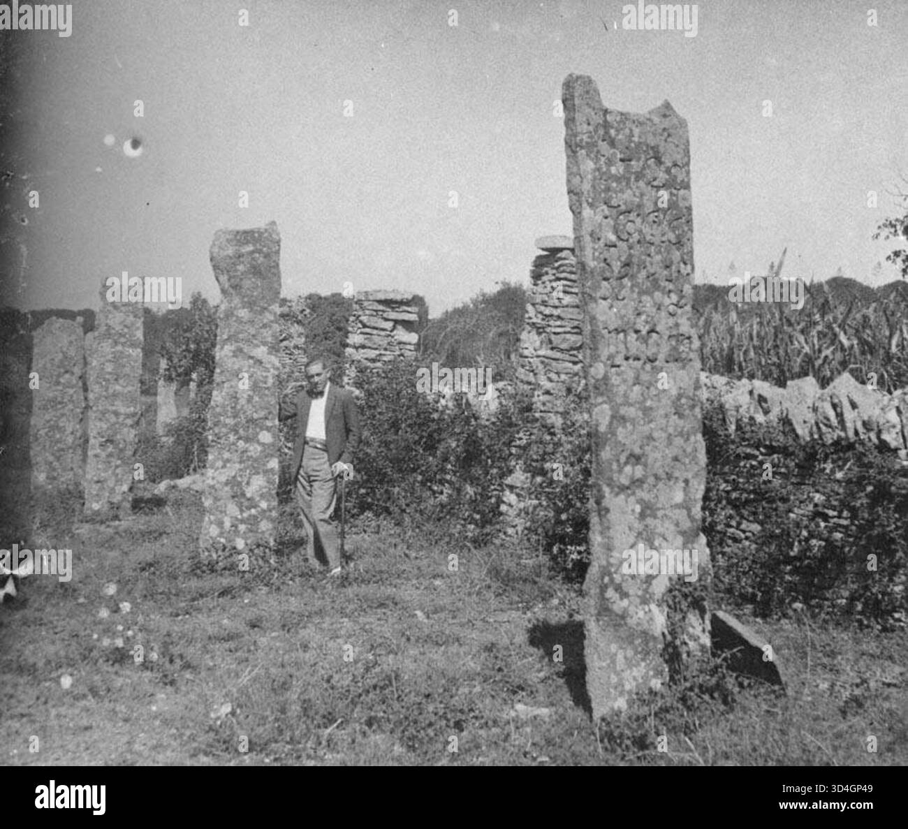 Pietre verticali con intagli e un uomo a Mas Joan, catturate da Antoni Gallardo i Garriga nel 1925. L'immagine presenta antichi segni di pietra e la presenza della vita umana in un ambiente rurale catalano. Foto Stock
