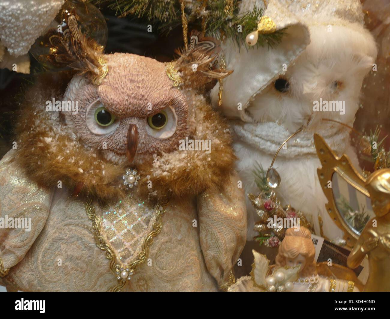 COLMAR, GERMANIA - 28 MAGGIO 2024 - due giocattoli morbidi, un gufo e un gatto, annidati tra ornamenti dorati e rami di pino su un albero di Natale, spolverati di fa Foto Stock