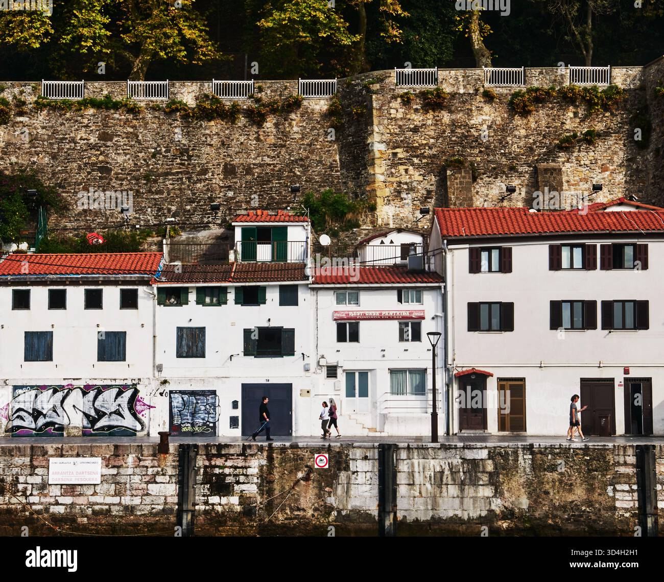 Fila di edifici con tetti di tegole rosse e un lungomare in pietra lungo Kaimingaintxo Plaza a Donostia-San Sebastian, nei Paesi Baschi della Spagna, in Europa Foto Stock