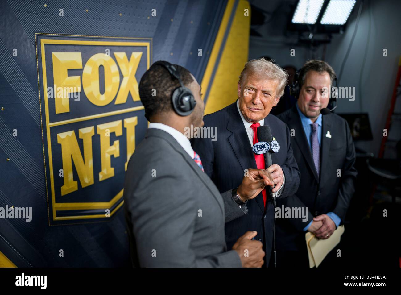 Landover, Stati Uniti. 9 novembre 2025. Il presidente degli Stati Uniti Donald Trump, al centro, si unisce agli atleti Kenny Albert, a destra, e Jonathan Vilma, a sinistra, durante la trasmissione in diretta alla cabina della Fox NFL mentre i Washington Commanders affrontano i Detroit Lions al Northwest Stadium, 9 novembre 2025 a Landover, Maryland. Credito: Daniel Torok/White House Photo/Alamy Live News Foto Stock