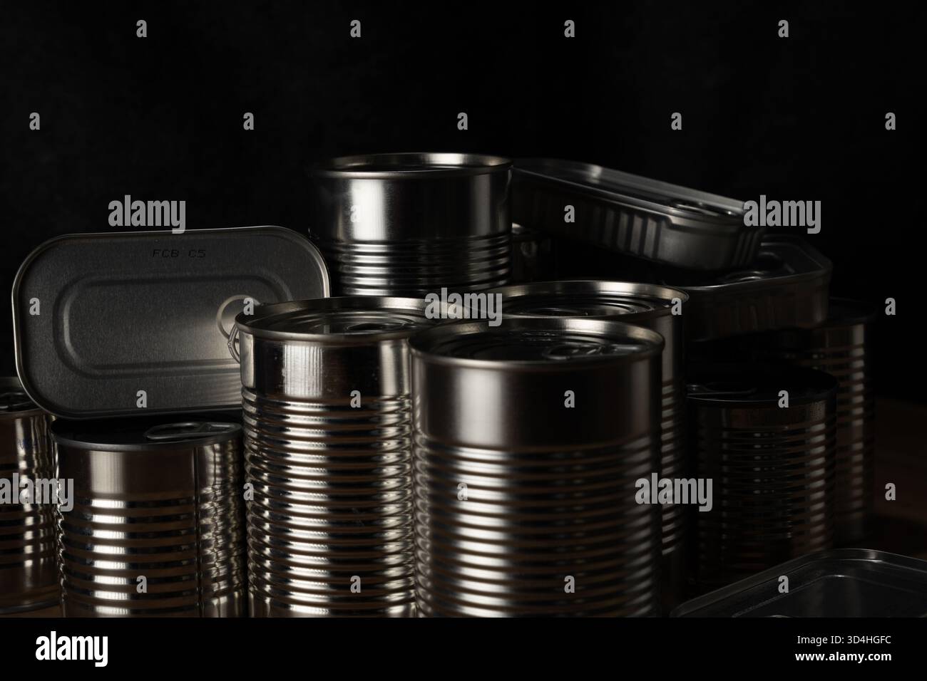Lattine metalliche per alimenti che offrono conservazione a lungo termine e provviste di dispensa su sfondo scuro Foto Stock