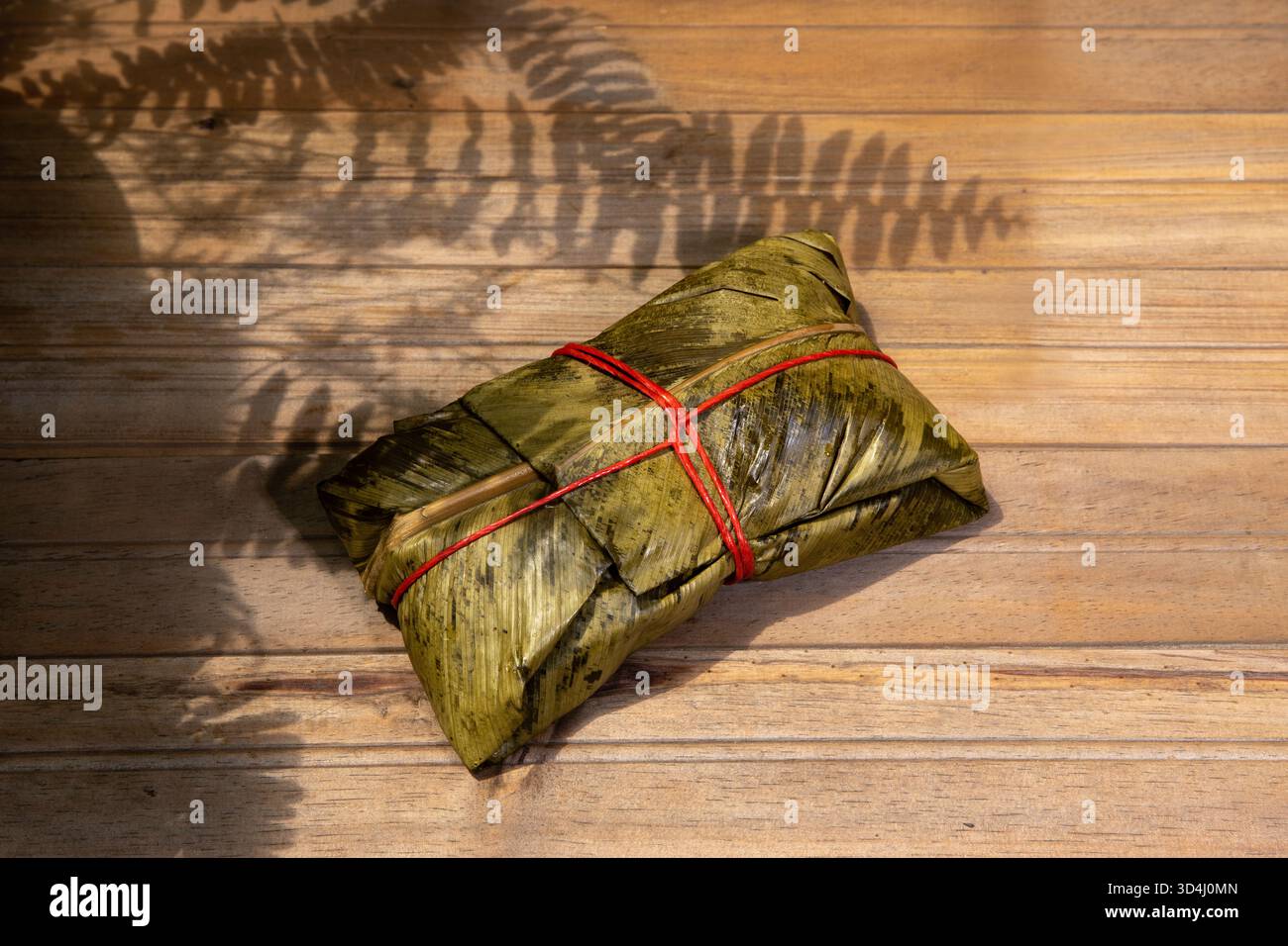 tamale tradizionale avvolto in foglie verdi, tipico piatto latino-americano a base di impasto di mais ripieno di carne, verdure e spezie. Cibo fatto in casa Foto Stock