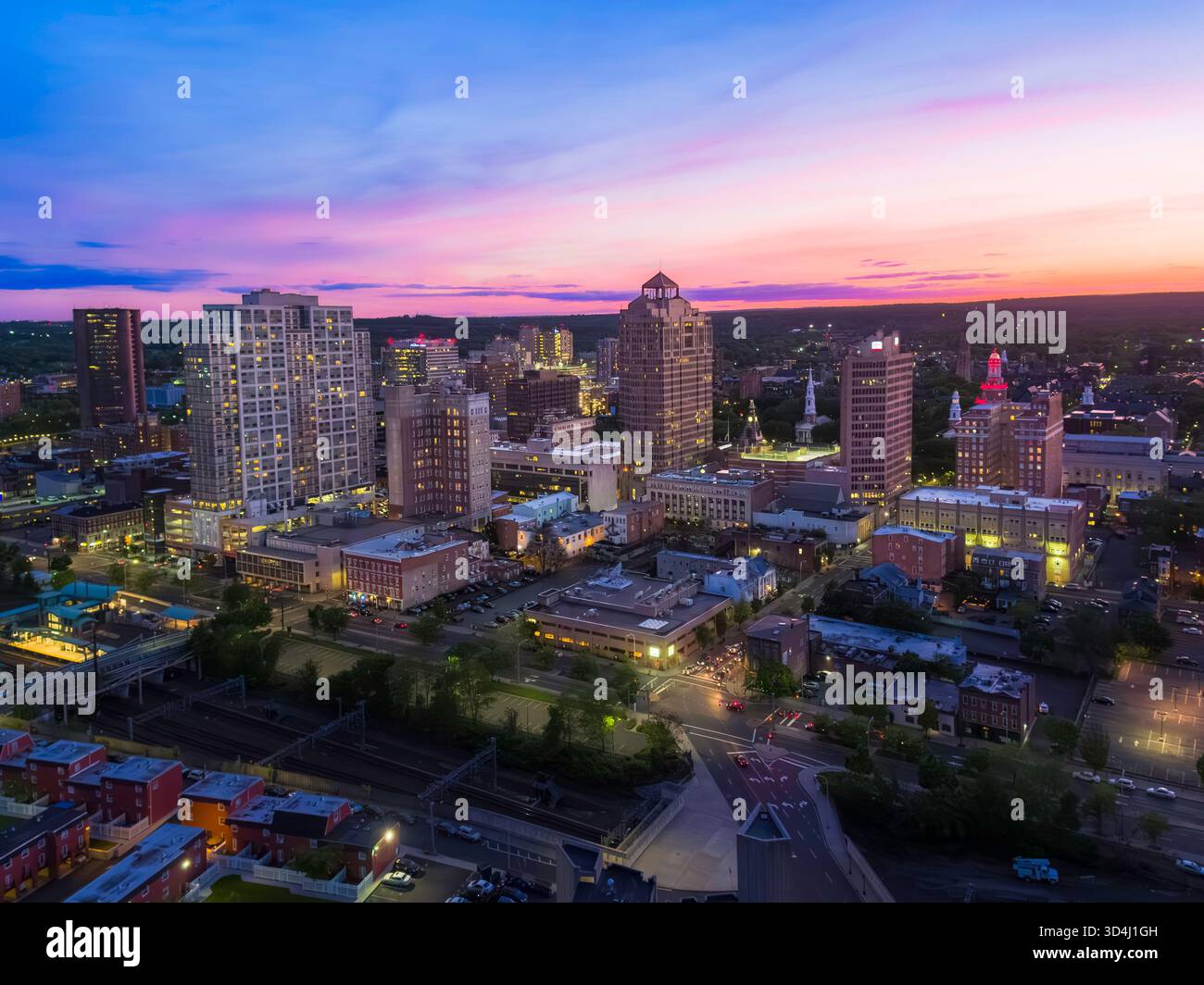 Il crepuscolo drappa lo skyline di New Haven, CT, in blu intenso e arancione, mentre le luci della città illuminano la scena. Foto Stock