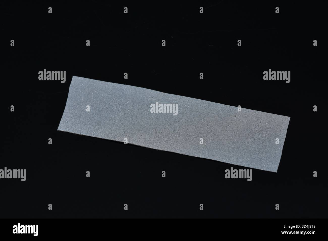 Nastro riflettente grigio per indumenti. Primo piano, messa a fuoco selettiva. Strisce altamente riflettenti per un abbigliamento ad alta visibilità nei periodi bui. Foto Stock