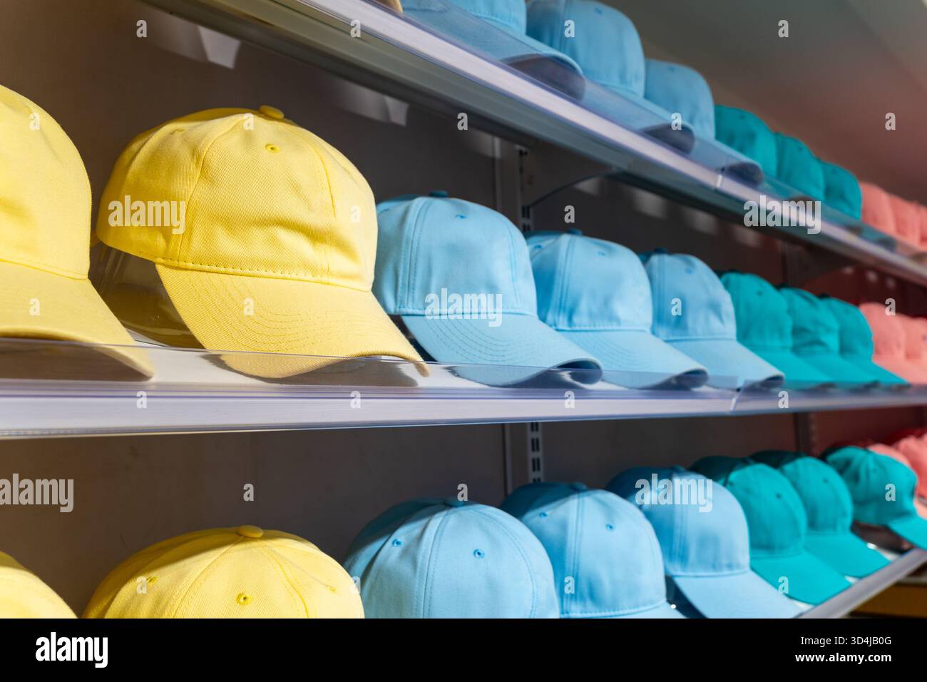 Cappellini da baseball colorati disposti ordinatamente sugli scaffali dei negozi in fila. Concetto di moda, vendita al dettaglio e stile. Foto Stock