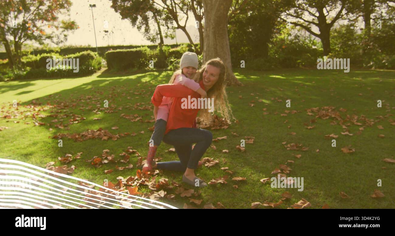 Inginocchiato donna di mezza età che trasporta un bambino sul retro del parco, indossa la maglietta rossa, bambino che indossa una giacca rosa Foto Stock