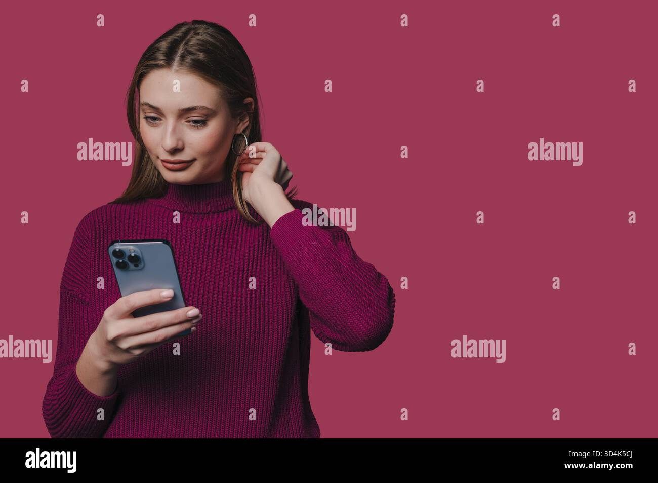 Donna che si impegna con lo smartphone in un ambiente di illuminazione da studio caldo Foto Stock