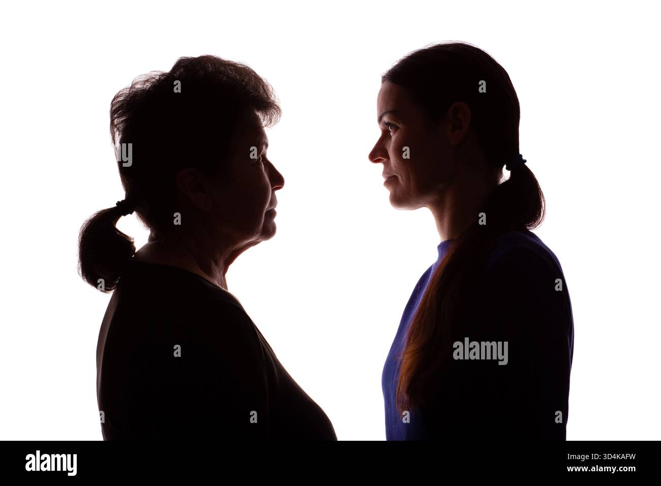 Silhouette scura di una donna anziana, una pensionata di fronte a una giovane donna, una madre e una figlia - isolata, sfondo bianco Foto Stock