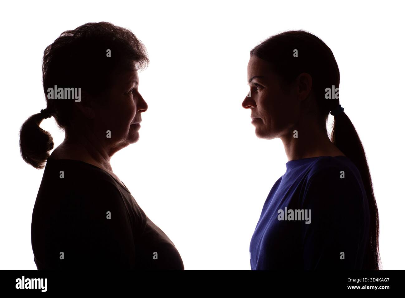 Silhouette scura di una donna anziana, una pensionata di fronte a una giovane donna, una madre e una figlia - isolata, sfondo bianco Foto Stock