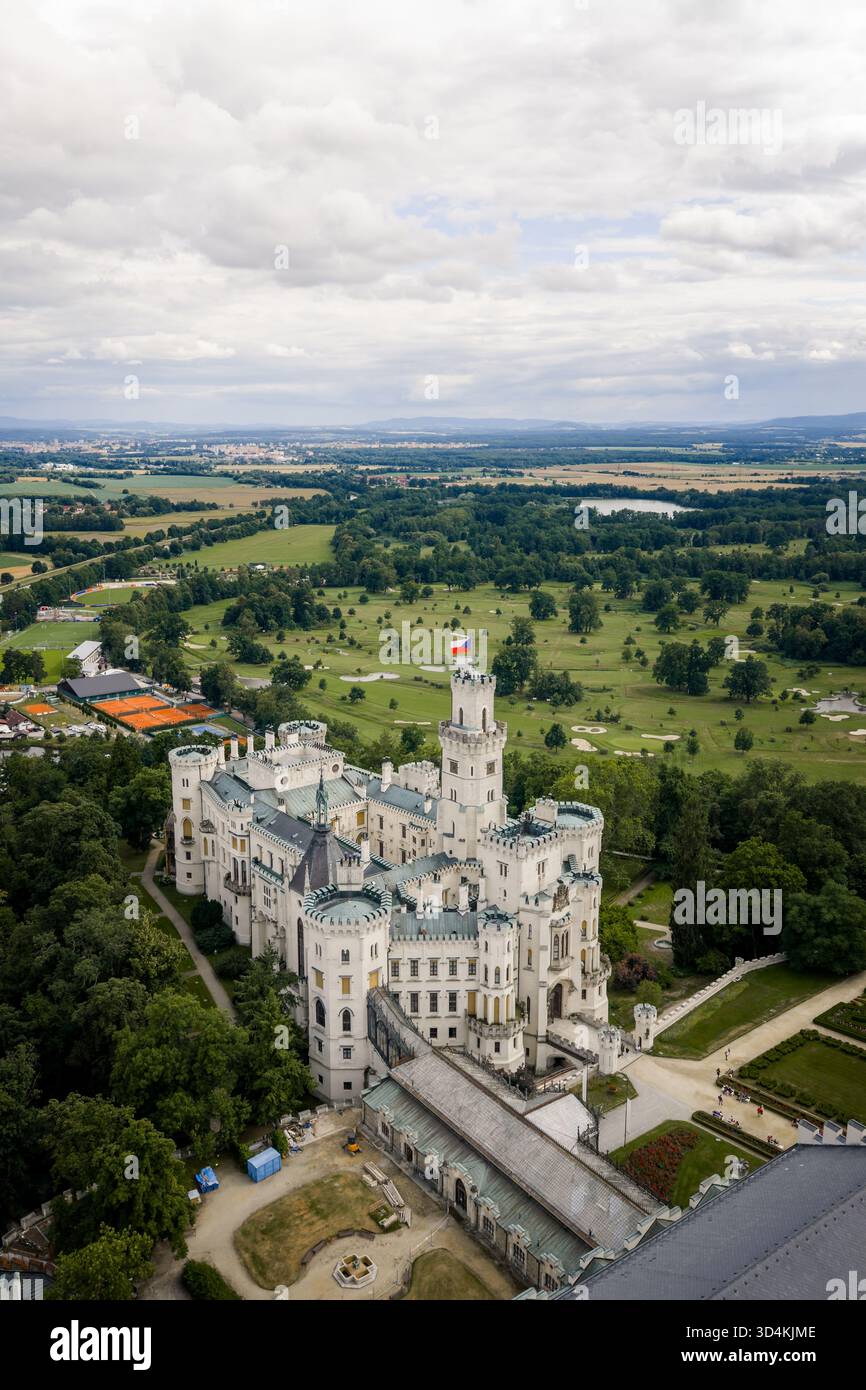Veduta aerea dell'incontaminato castello bianco di Zamek, un faro di eleganza architettonica tra foreste verdeggianti e prati curati, Hluboka nad Vltavou, Ji Foto Stock