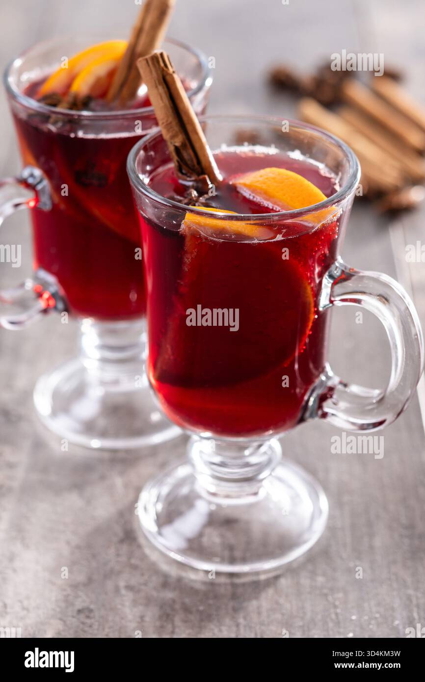 VIN brulé con bastoncini di arancia e cannella e decorazioni natalizie su un tavolo in legno Foto Stock