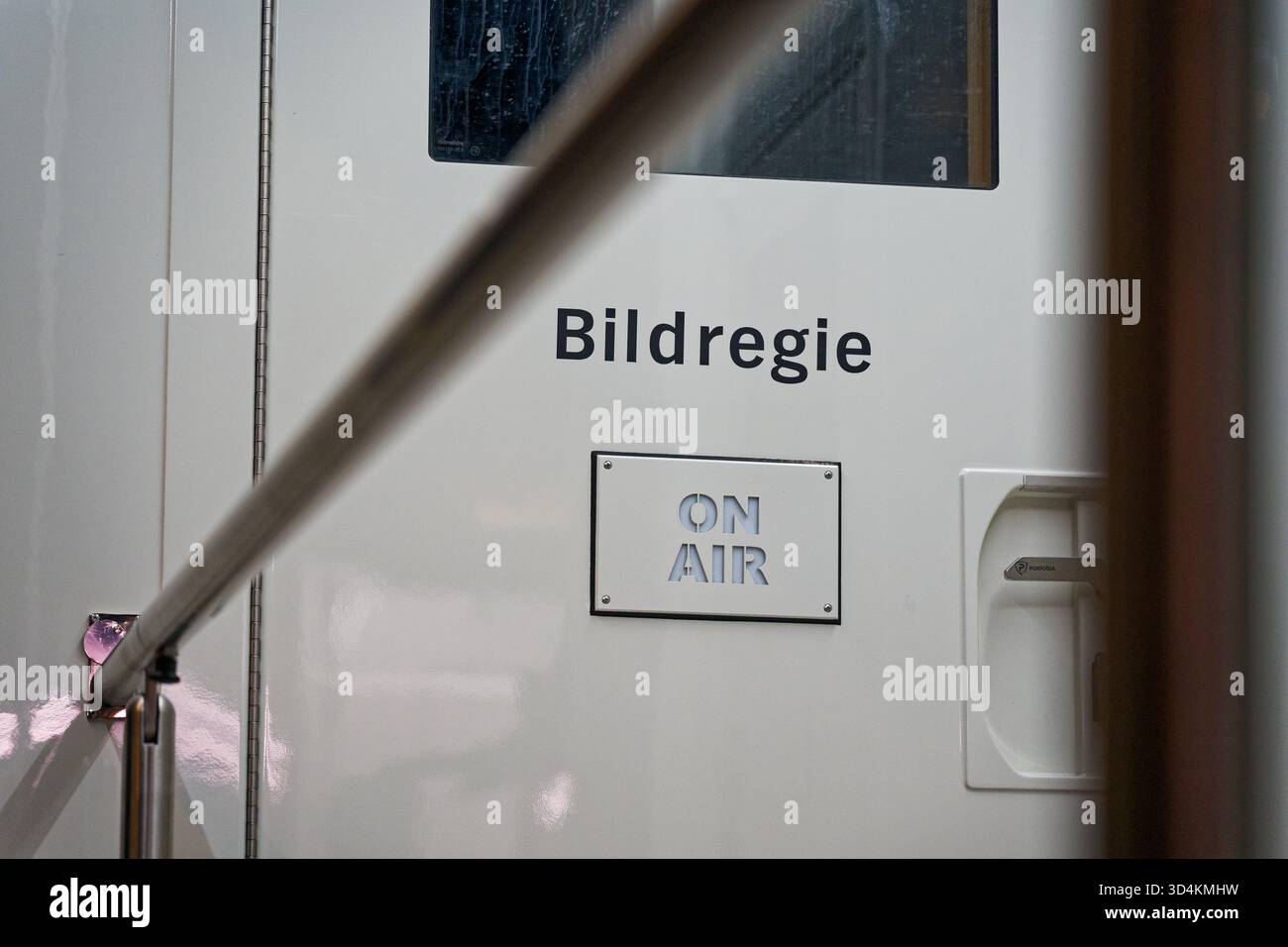Ingresso di una sala di controllo TV professionale denominata Bildregie con un cartello luminoso IN ONDA, che simboleggia la trasmissione in diretta, il lavoro di squadra creativo e Real-ti Foto Stock