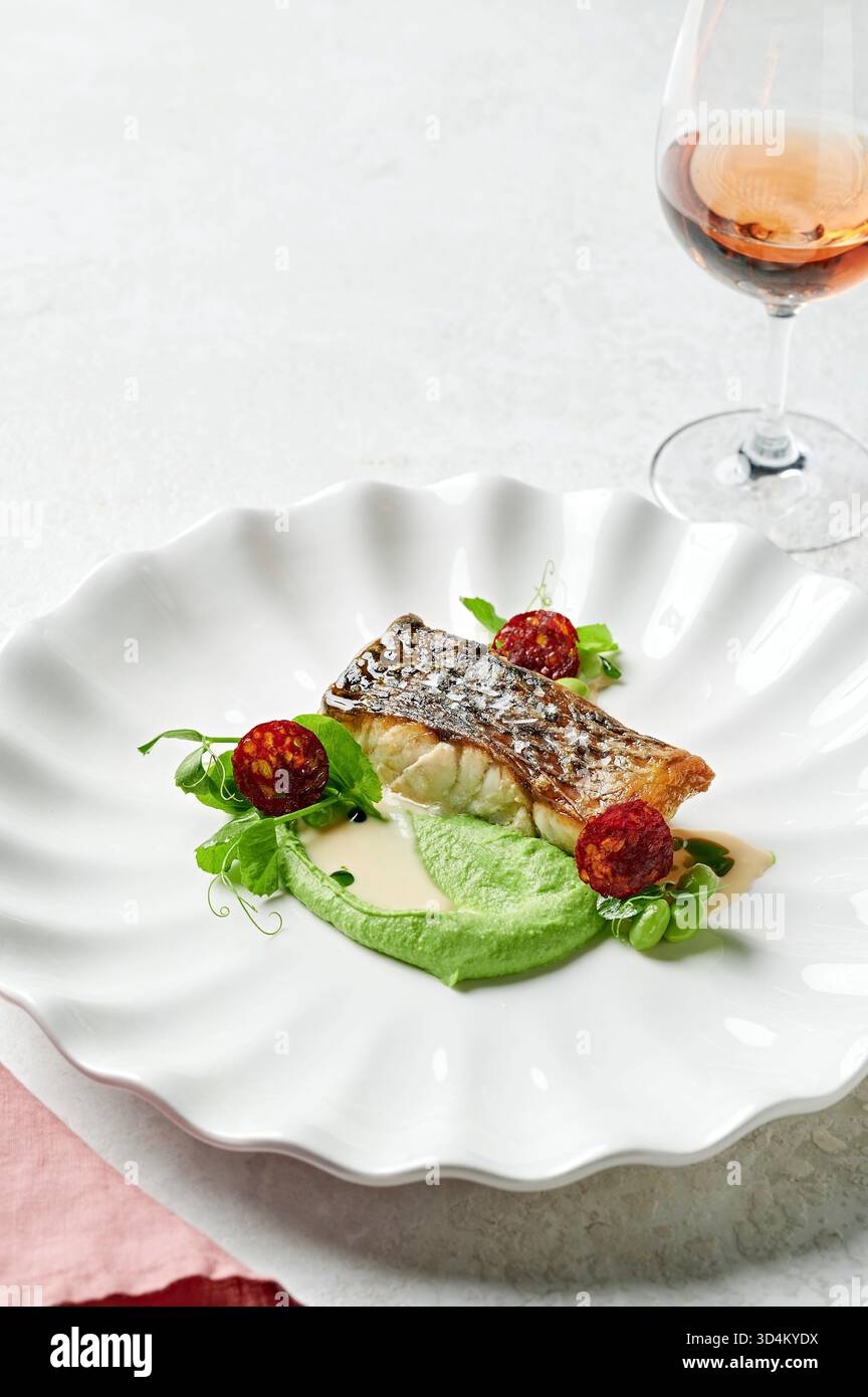 Filetto di Barramundi, purea di piselli, crema di miso, chorizo croccante, edamame, tendini di piselli da neve Foto Stock