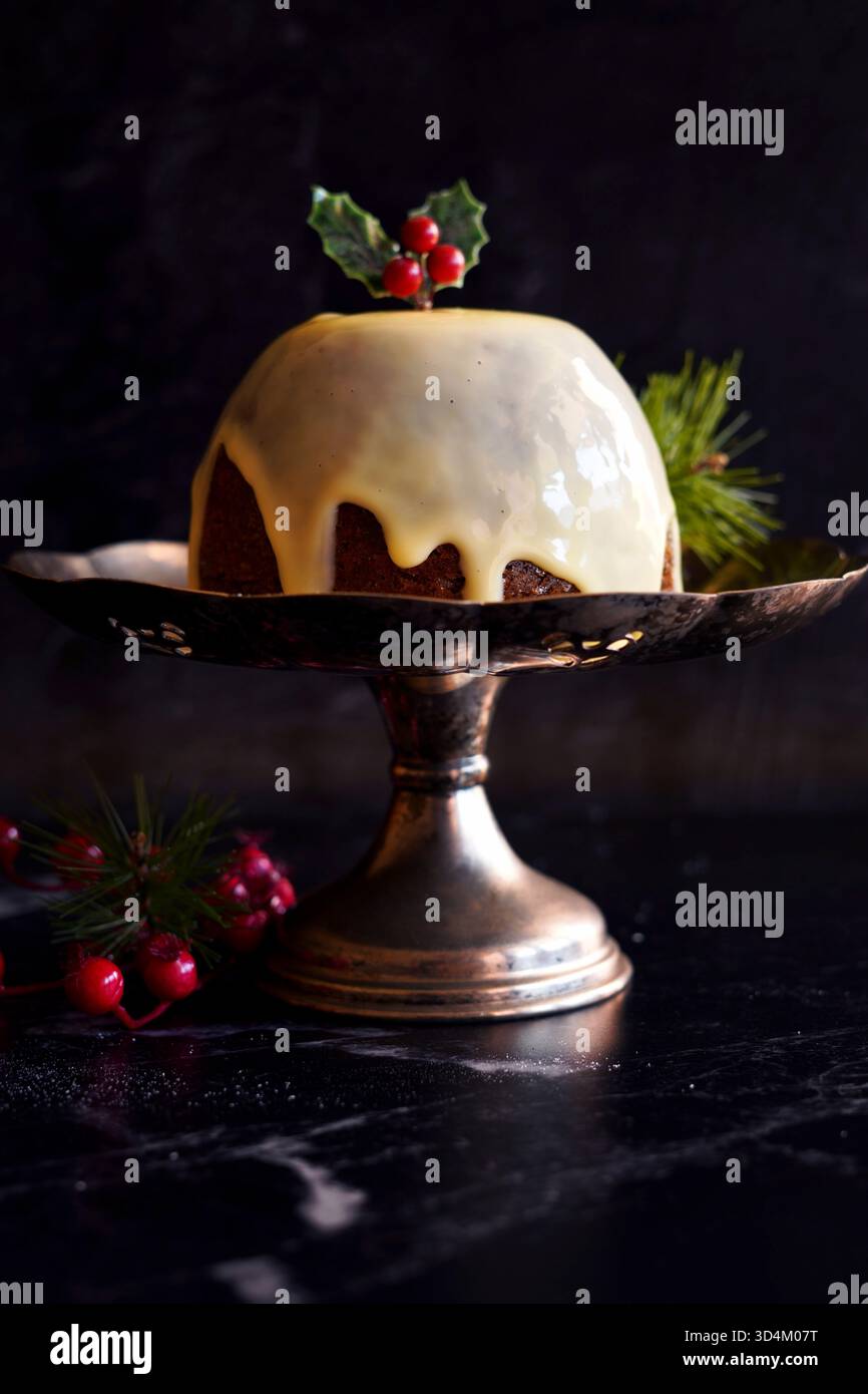 Dessert natalizio in stile inglese, servito con tradizionale crema di brandy, su sfondo di marmo nero. Foto Stock
