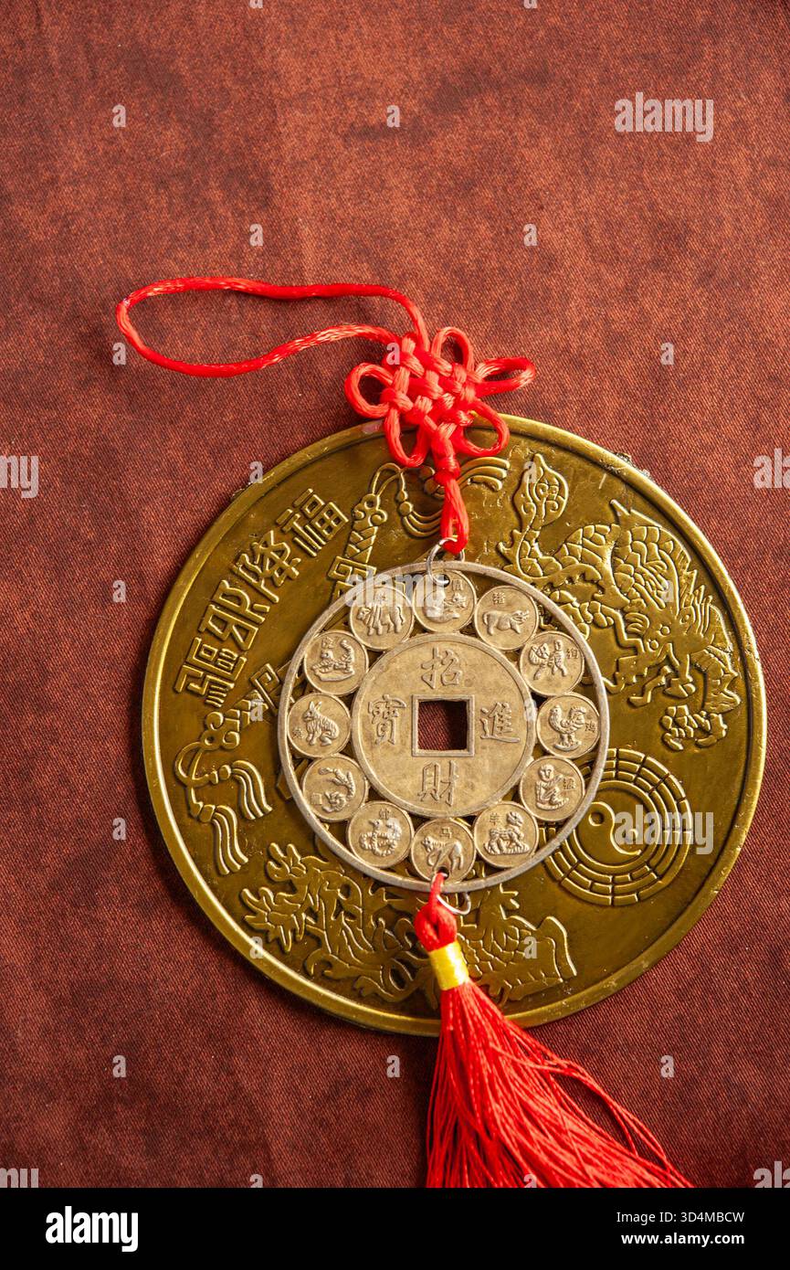 Tradizionale moneta cinese del Feng Shui con simboli zodiacali e stringa rossa per buona fortuna e prosperità Foto Stock