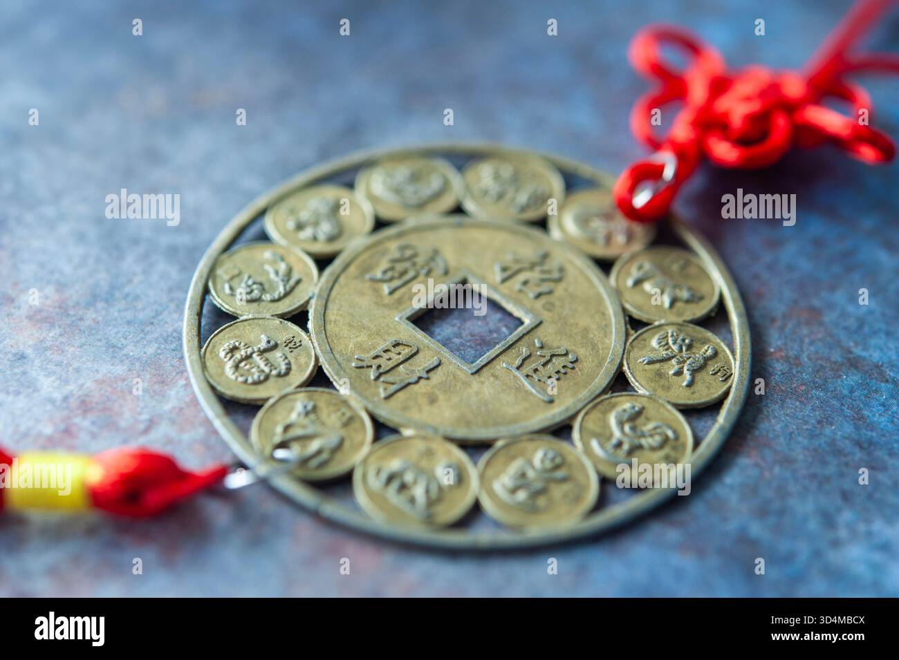 Tradizionale moneta cinese del Feng Shui con simboli zodiacali e stringa rossa per buona fortuna e prosperità Foto Stock