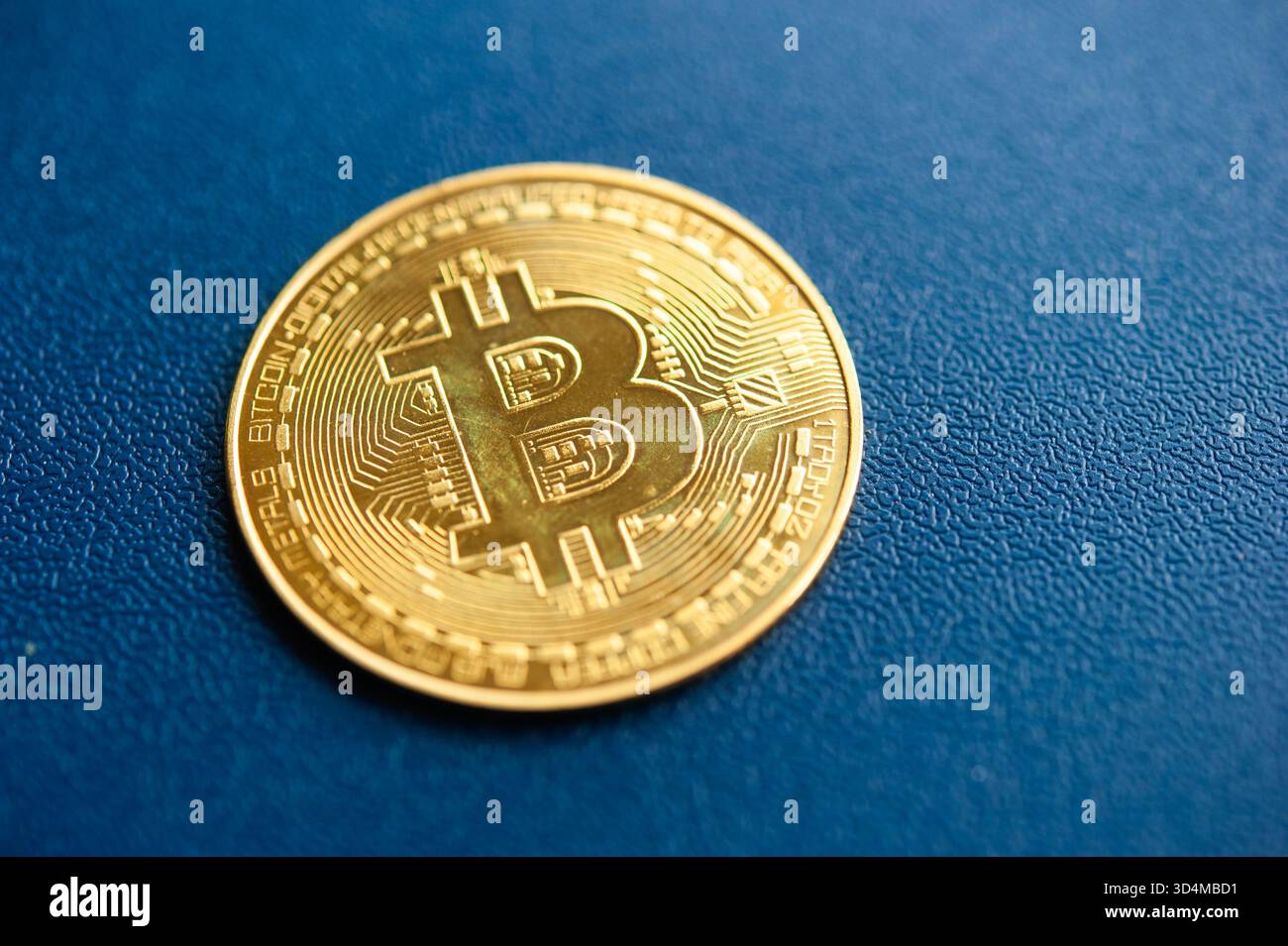 Moneta fisica Gold Bitcoin su sfondo blu con texture che rappresenta criptovaluta e finanza digitale Foto Stock
