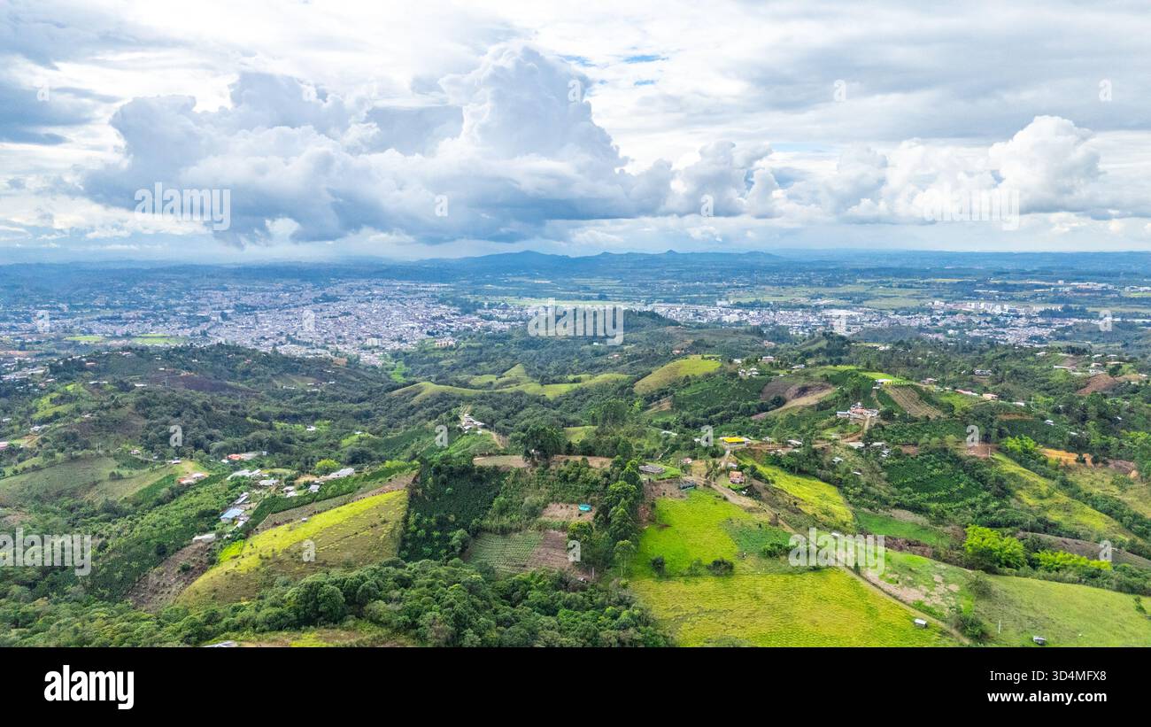 Splendida vista aerea che mostra le lussureggianti colline verdi e il vibrante paesaggio di Popayán, Cauca, Colombia, circondato da nuvole. Foto Stock
