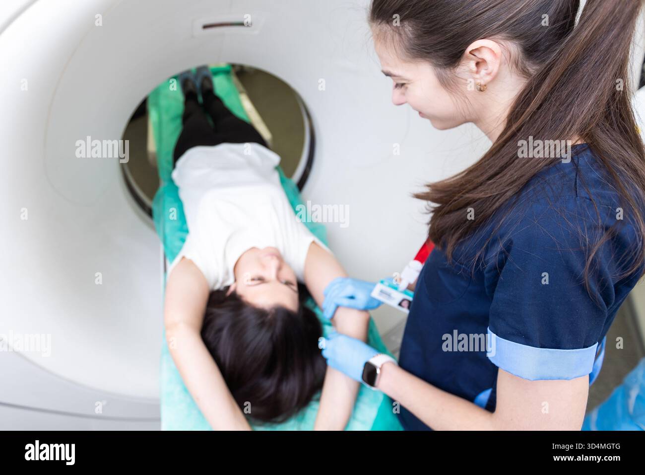 Il tecnico di scansione TC si affaccia sul paziente nello scanner di tomografia computerizzata durante la preparazione della procedura. Paziente donna che entra nello scanner TC. Foto Stock