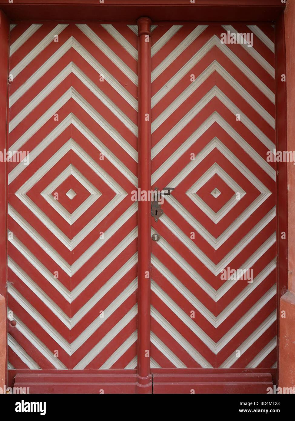 Porta storica in legno a doppia ala con motivo a rombi rosso-bianco e vecchia maniglia. Copyspace Foto Stock