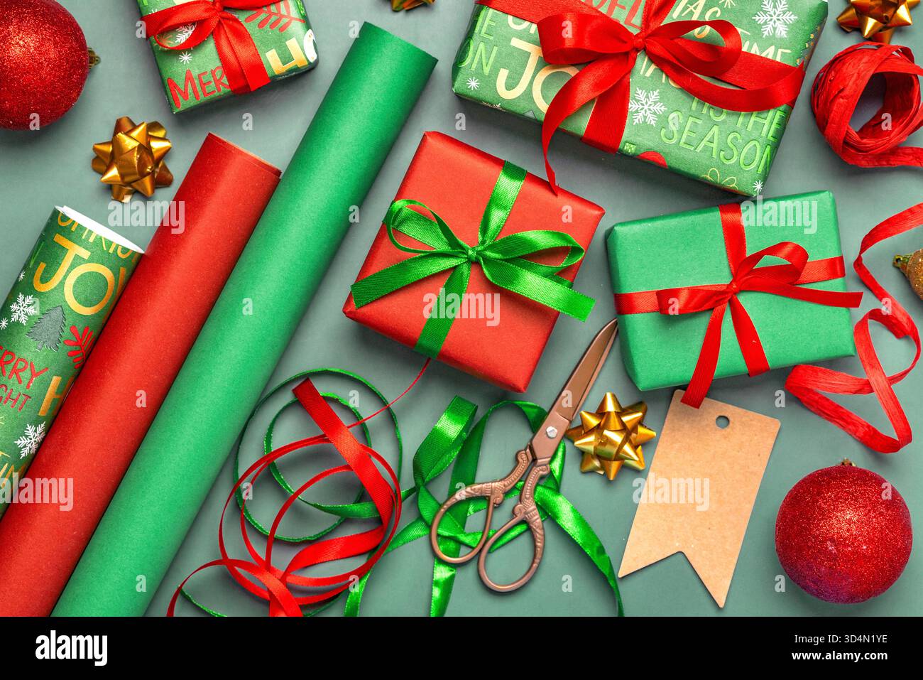 Vista dall'alto di confezioni regalo di Natale, carta da imballaggio natalizia, forbici e articoli per l'imballaggio di regali natalizi su sfondo grigio. Backg di Natale Foto Stock
