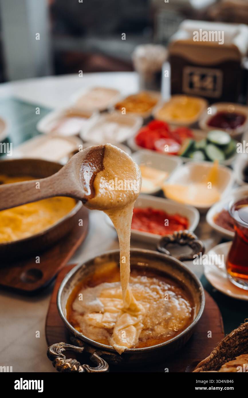 Primo piano di una tradizionale colazione turca con kuymak, un piatto regionale a base di farina di mais, burro e formaggio fuso, servito con vari piatti Foto Stock