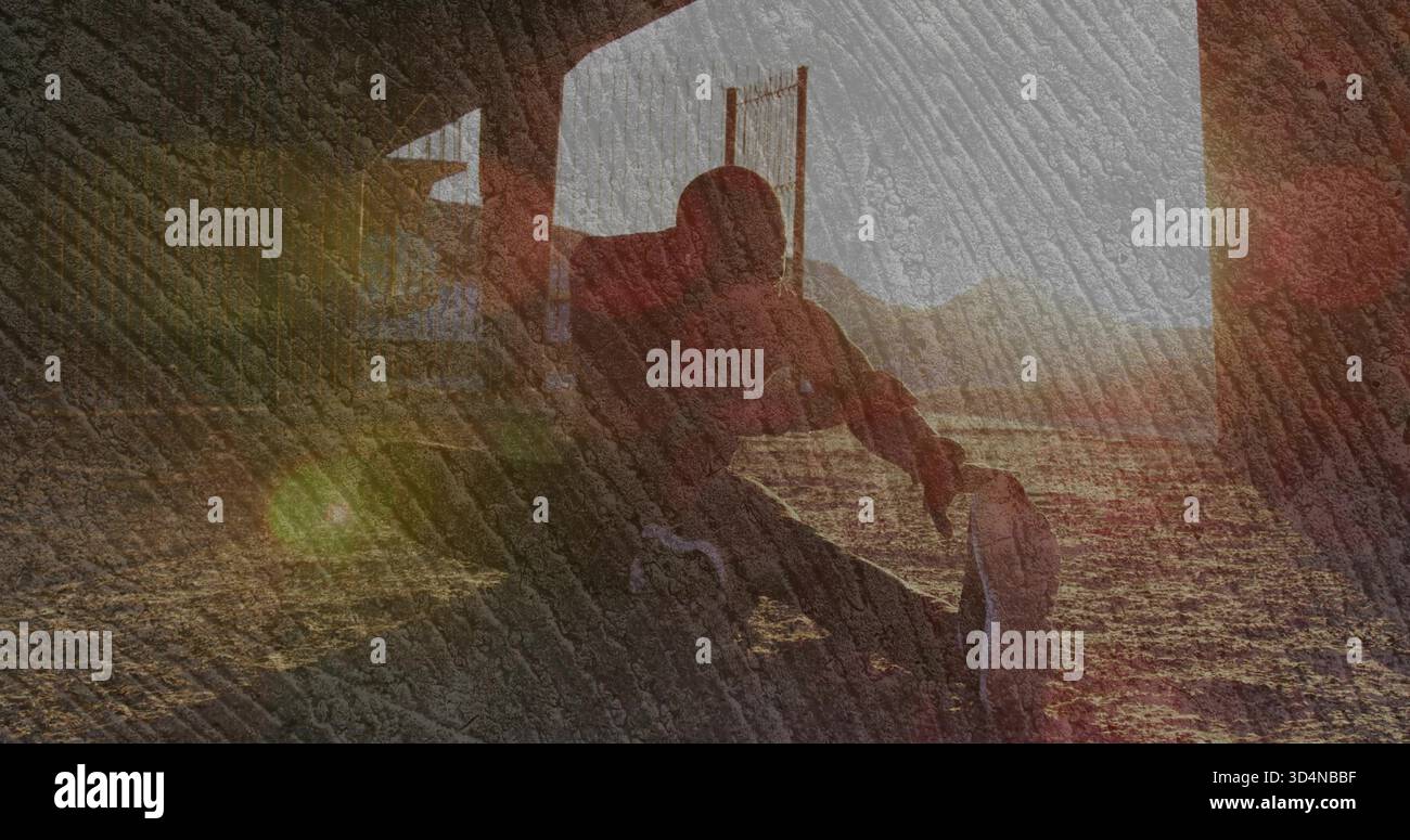 Uomo seduto con silhouette che indossa pantaloncini sportivi e sneaker sotto l'arco, che cattura il sole basso Foto Stock