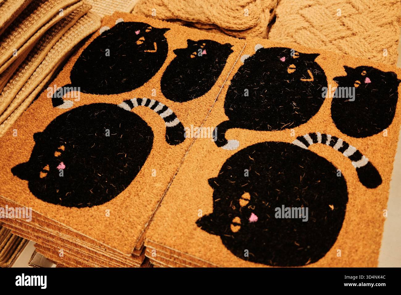 Tappetini marroni con gatti neri con naso rosa e code a righe disposti in un negozio. Il concetto trasmette giocosità, fascino e atmosfera accogliente Foto Stock