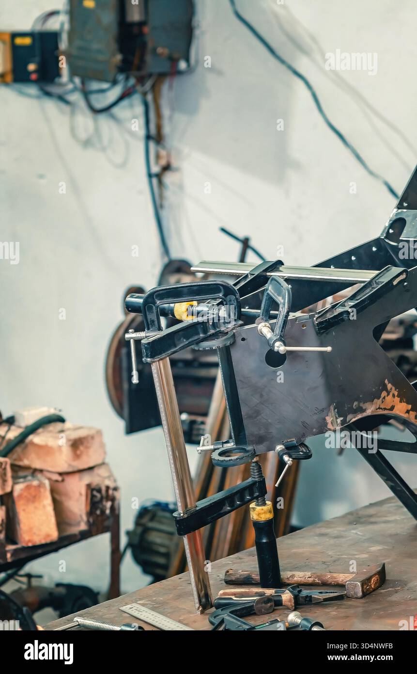 Il morsetto metallico tiene insieme le parti in ferro. Preparazione delle parti metalliche per la saldatura. Informazioni generali sulle officine industriali. Foto Stock