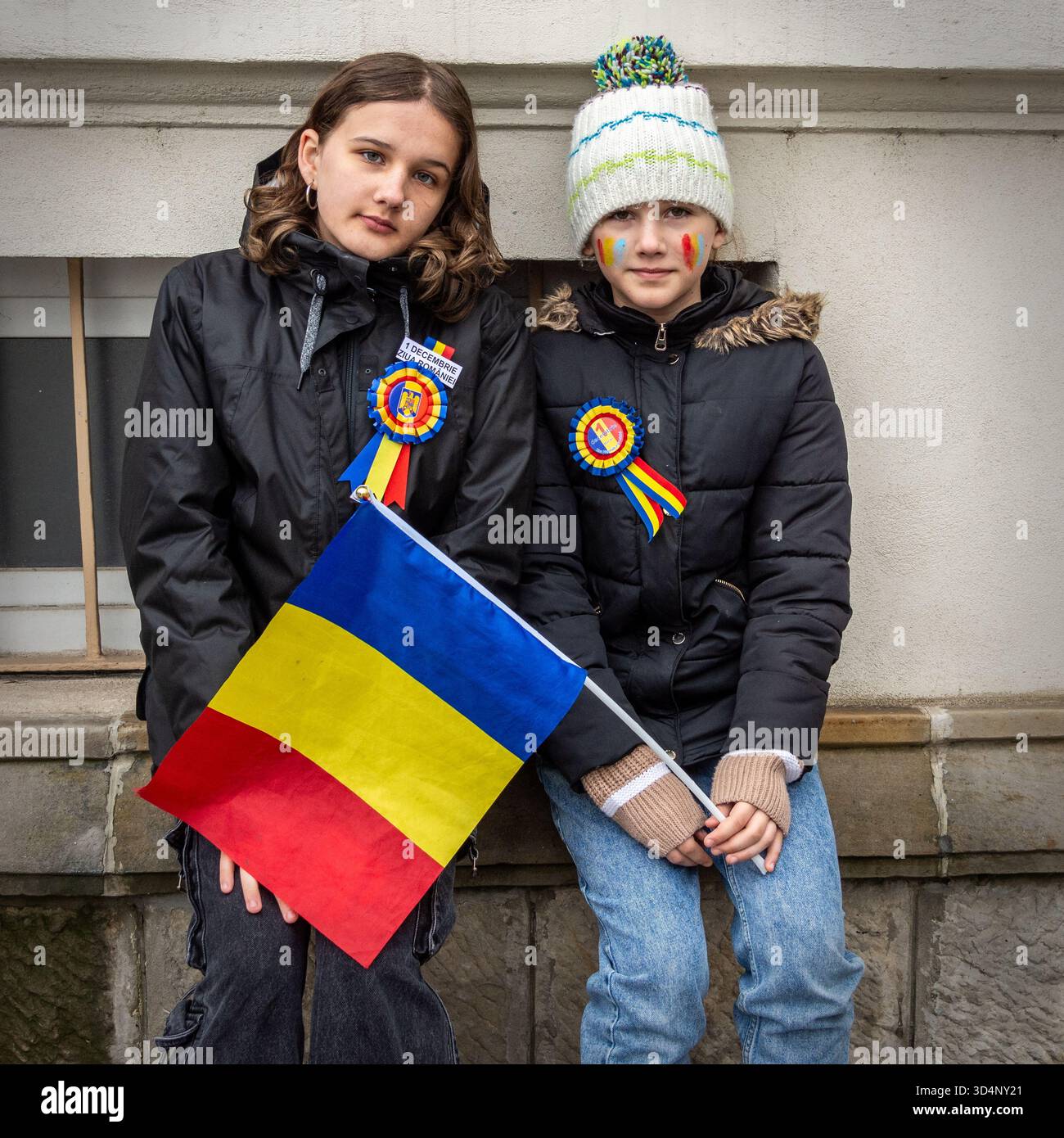 Due bambini con nastri tricolori e bandiera rumena che celebrano la giornata nazionale a Bacău, Romania. Foto Stock