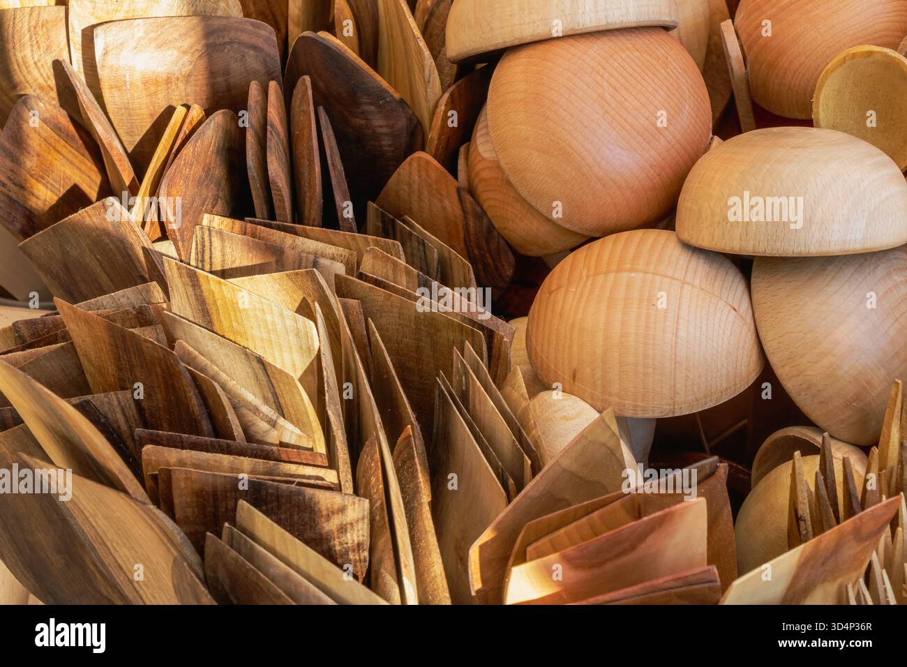 Una vista dettagliata di cucchiai di legno fatti a mano, spatole e ciotole esposte in una fiera dell'artigianato. Le texture lucide e le tonalità del legno naturale esaltano il mestiere Foto Stock