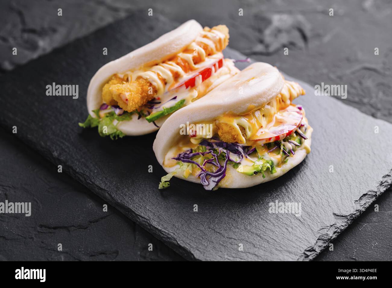 Cibo, gustosi panini di pollo bao serviti su un piatto di ardesia, perfetti per i menu della moderna cucina asiatica Foto Stock