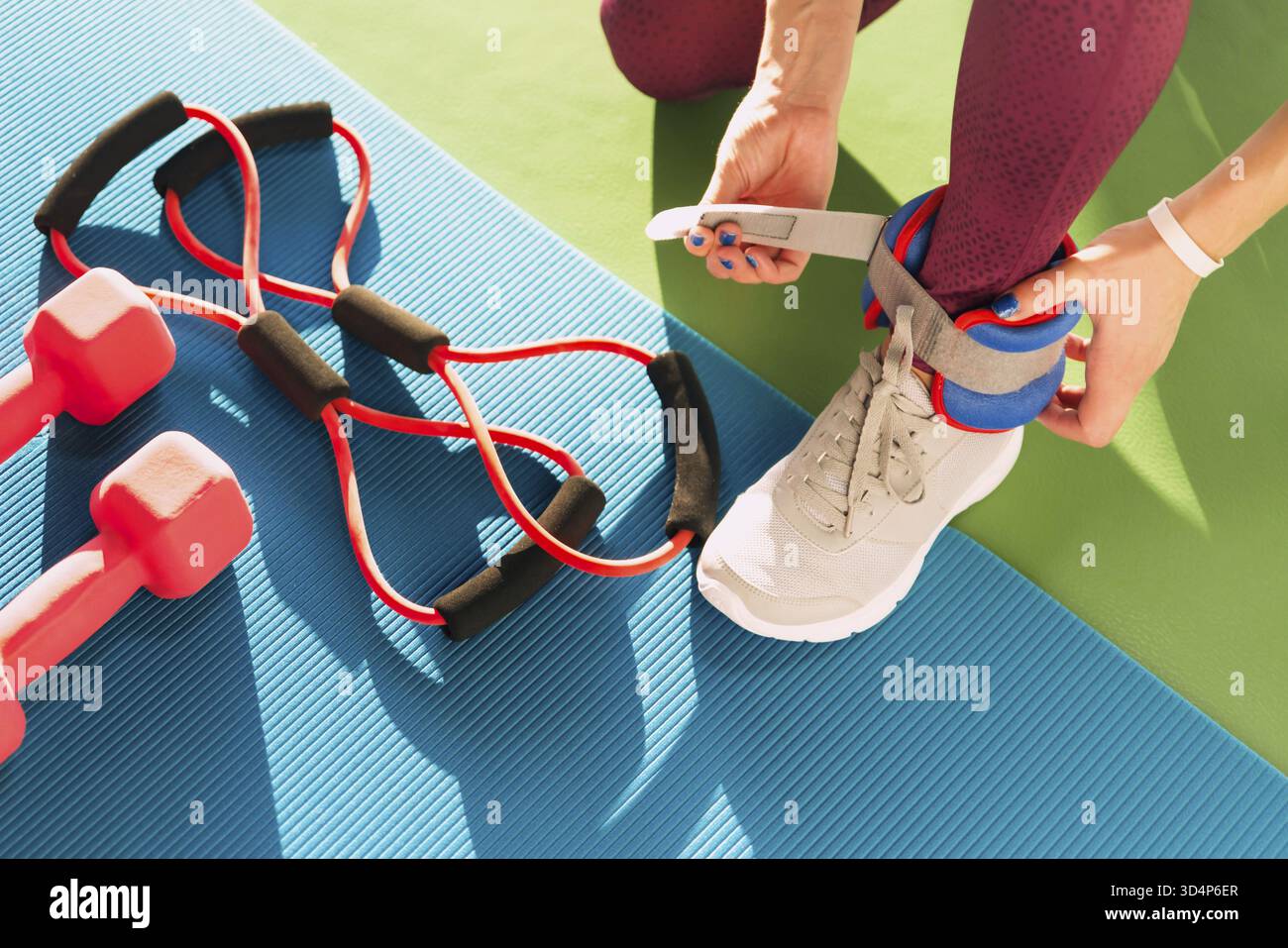 Donna mettendo sulla caviglia wights prima che lei inizia un allenamento in palestra fitness e salute Foto Stock