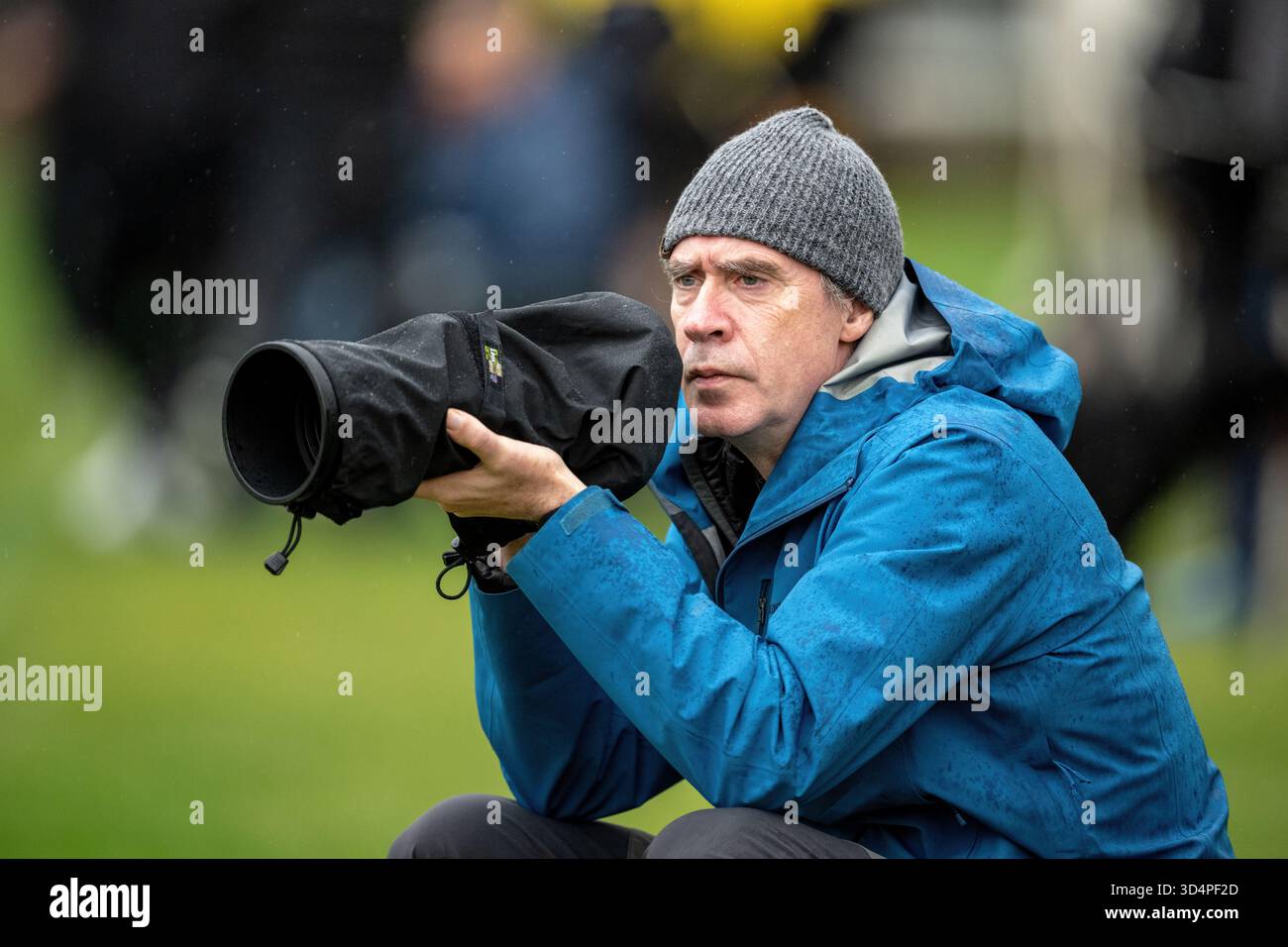 Il fotografo Phillip Hughes fotografa immagini sportive sotto la pioggia a Fort William, in Scozia, per i giornali provinciali dell'Oban & Lochaber Times. Foto Stock