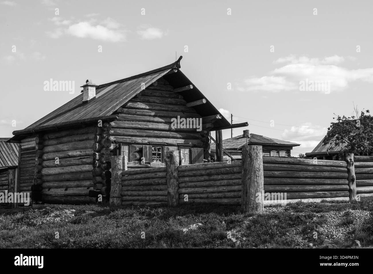 Vista in bianco e nero di un'antica casa rurale in legno in un tranquillo villaggio Urale della Russia, che mostra la tradizionale architettura rustica e la vita di campagna Foto Stock