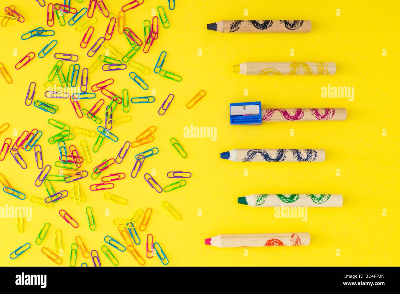 Layout colorato realizzato con graffette e pastelli in cera su sfondo giallo chiaro. Concetto scolastico minimale. Stile piatto. Vista dall'alto. Foto Stock