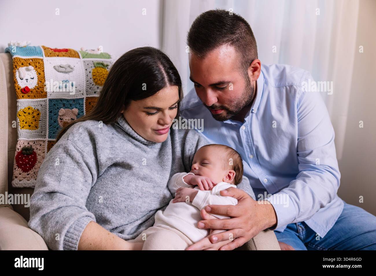 Genitori felici che cullano il neonato che dorme a casa Foto Stock