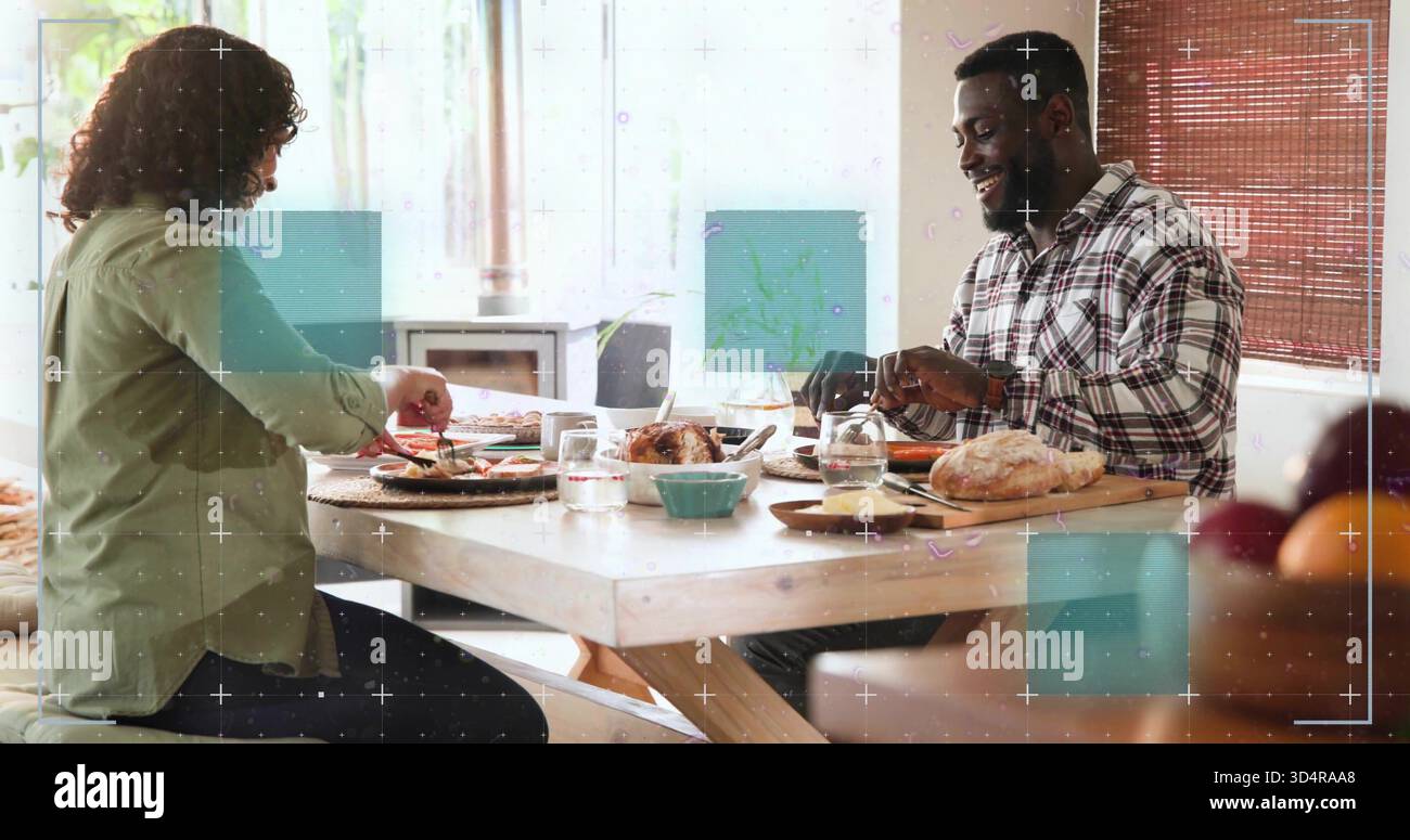 La coppia che indossa una camicia a quadri e una camicia verde che taglia il pollo arrosto al tavolo di casa con il pane Foto Stock
