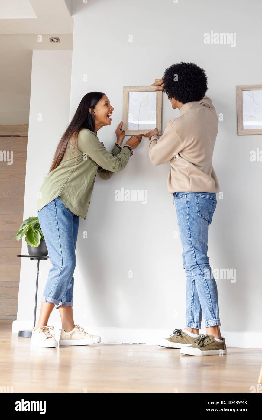 Appendere diverse coppie che regolano la cornice in legno sulla parete del corridoio, con tavolino laterale e pianta Foto Stock