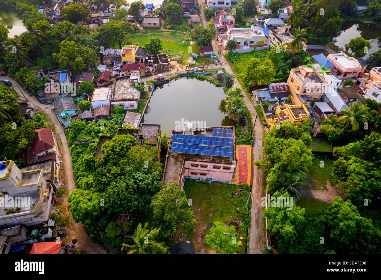 Drone aereo di tetti a pannelli solari accanto al corpo d'acqua e agli alberi nella città suburbana indiana. Foto Stock