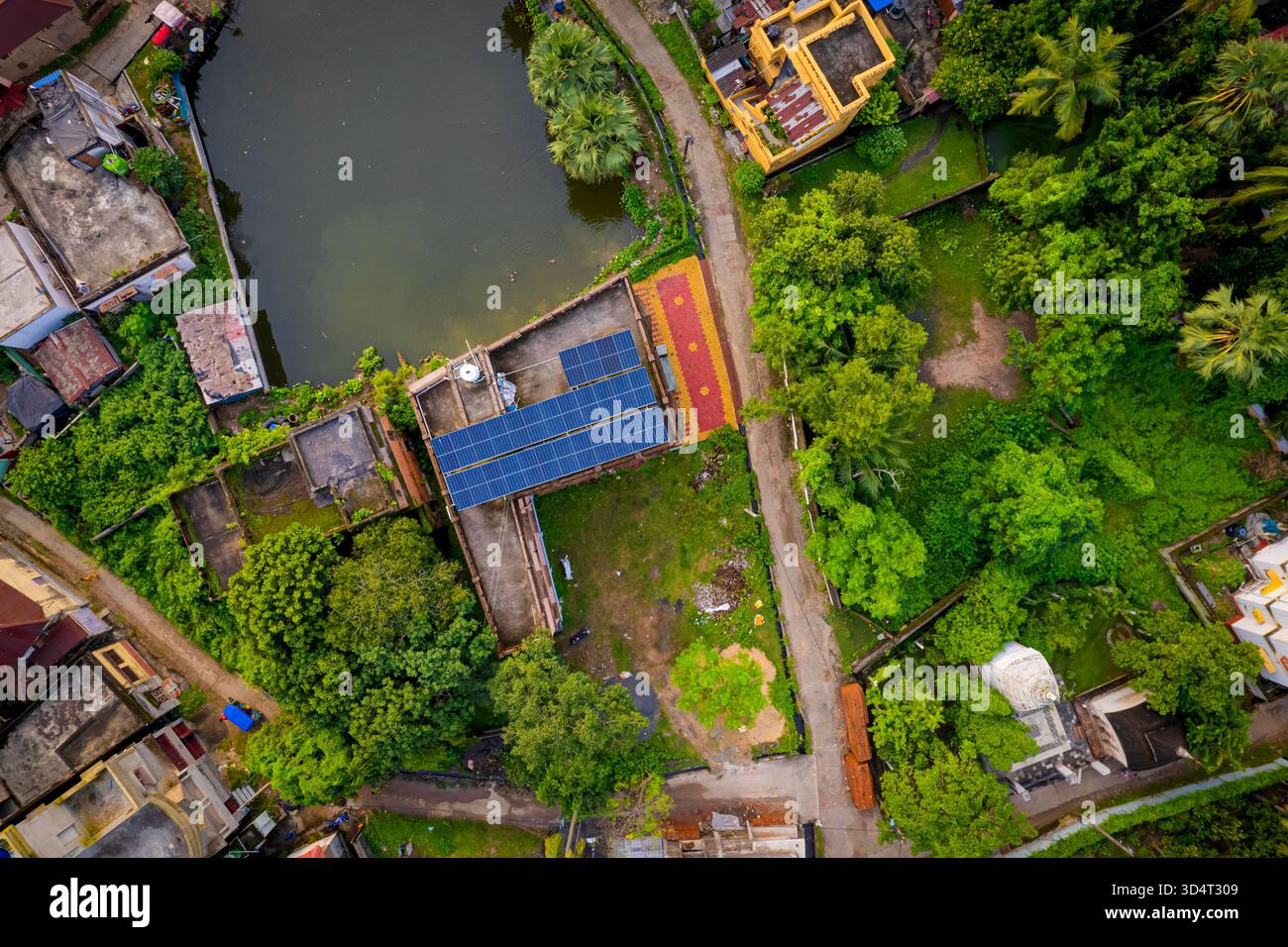 Drone aereo di tetti a pannelli solari accanto al corpo d'acqua e agli alberi nella città suburbana indiana. Foto Stock