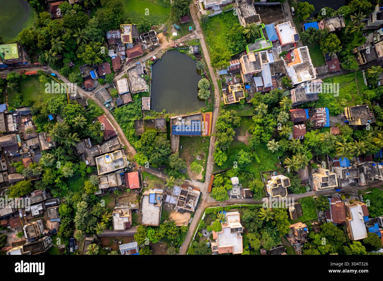 Drone aereo di tetti a pannelli solari accanto al corpo d'acqua e agli alberi nella città suburbana indiana. Foto Stock